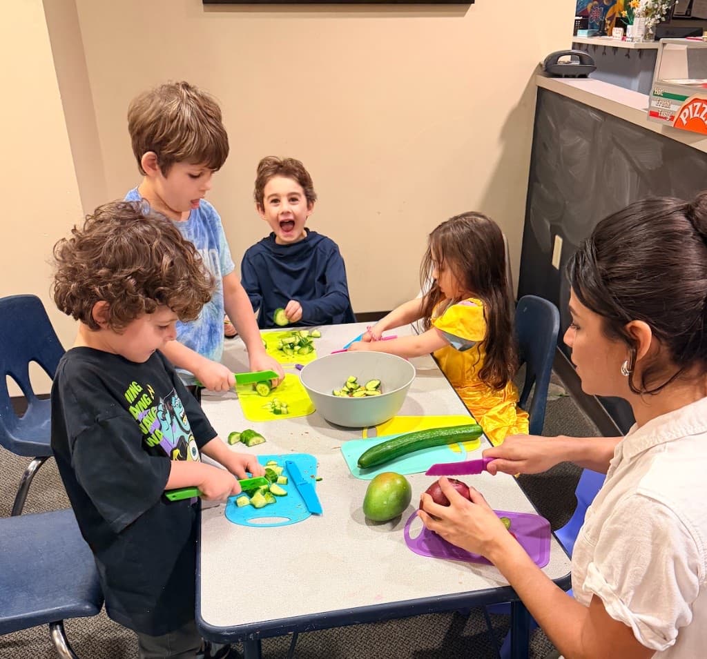 Children cutting vegetables with Monica Hidalgo during a cooking class