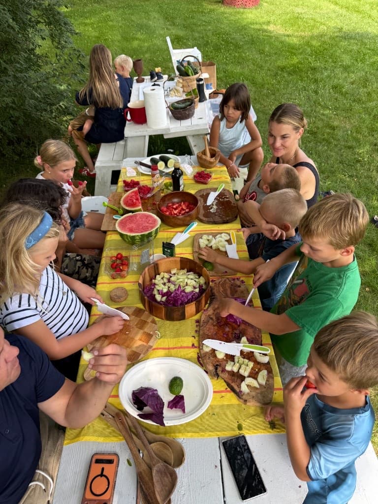 Families and children preparing food together at an outdoor community workshop